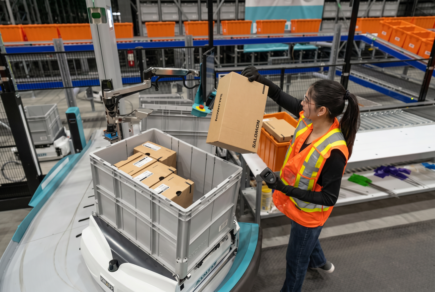 Préparatrice logistique préparant des commandes dans un entrepôt automatisé de l'industrie du sport et de l'outdoor.